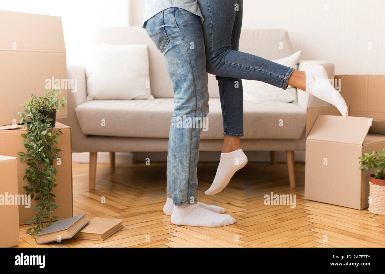 Afro marito sollevando la moglie tra le caselle mobili interni, ritagliato Foto Stock