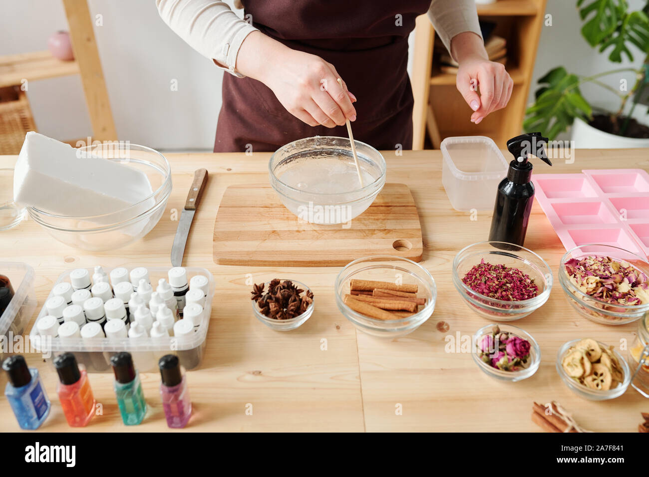Giovani donne in grembiule in piedi dal tavolo e la miscelazione di sapone liquido nella massa della vetreria Foto Stock