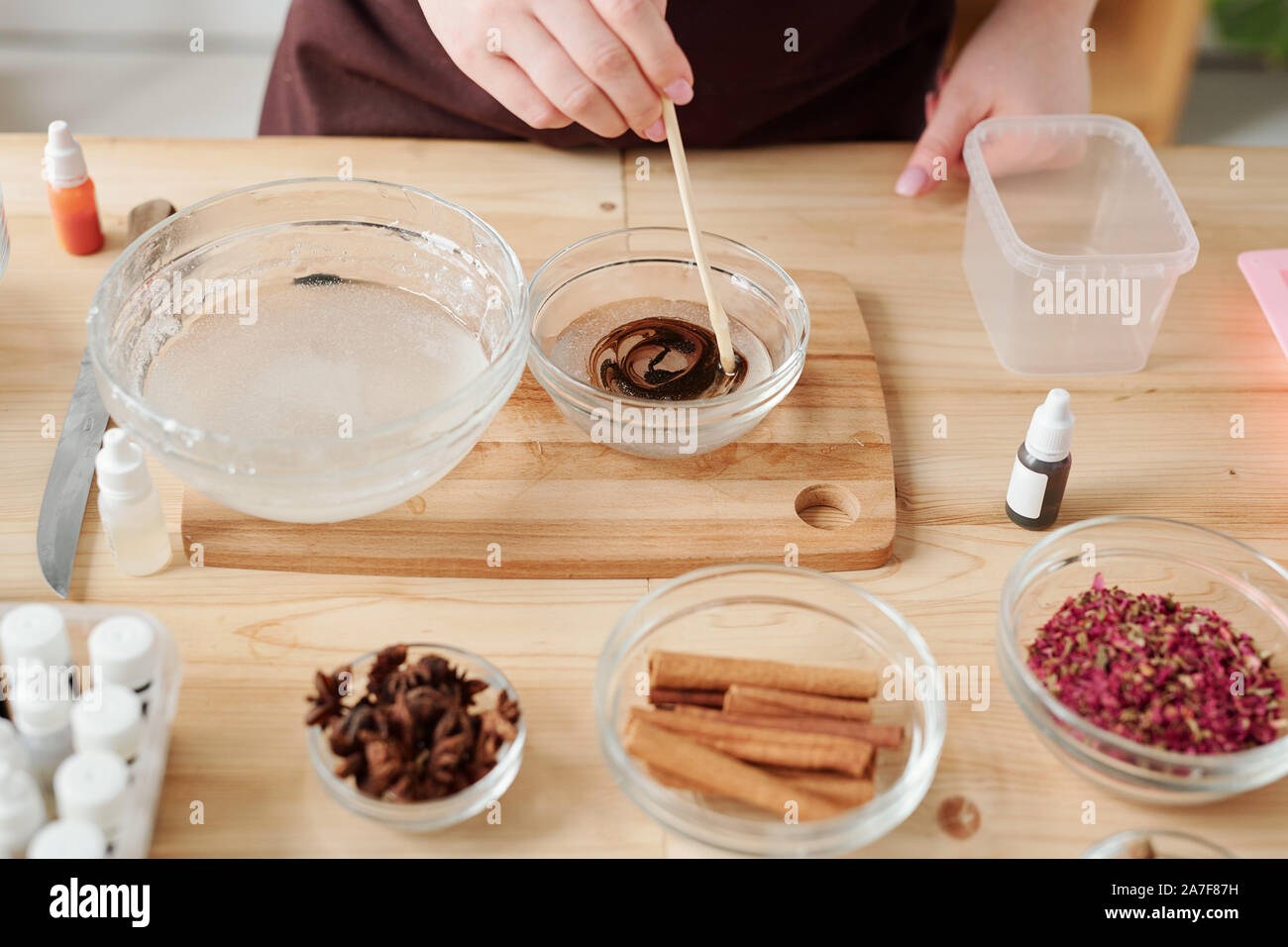 Mani femminili di miscelazione di sapone liquido con la massa di cioccolato in essenza della vetreria Foto Stock