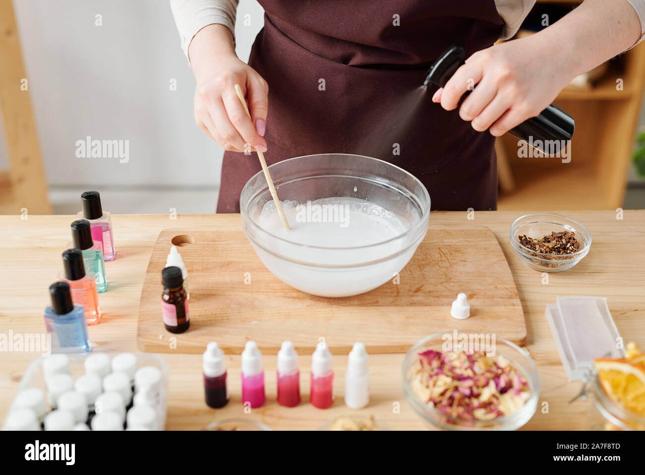 Mani femminili di spruzzare olio aromatico nel sapone liquido nella massa della vetreria Foto Stock