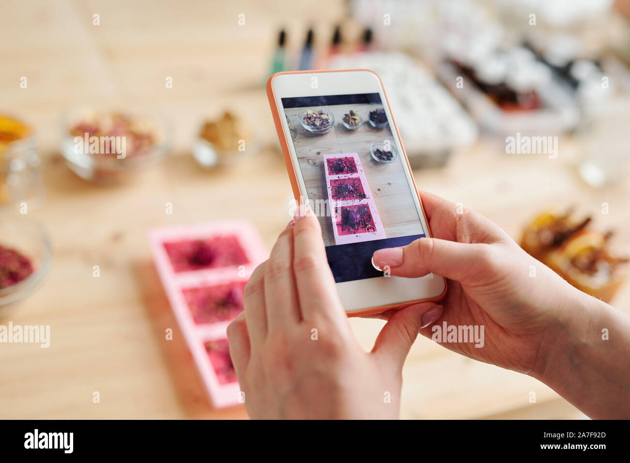 Le mani della ragazza con lo smartphone tenendo la foto del sapone artigianale in stampi in silicone Foto Stock