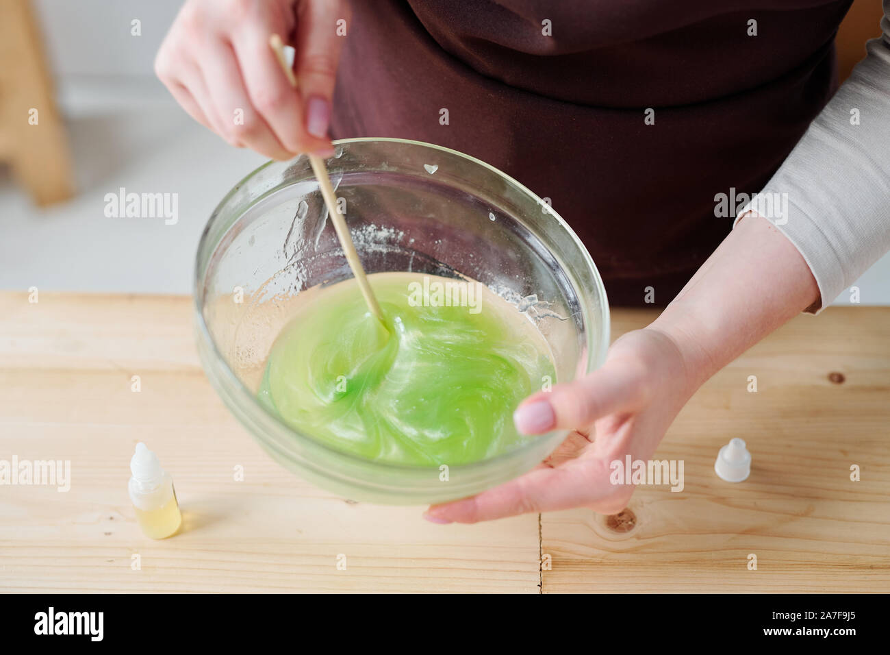 Donna liquido di miscelazione la massa di sapone con colore verde in vetreria con bastone di legno Foto Stock
