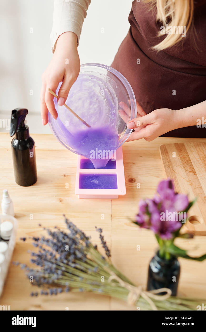 Giovane donna versando profumata lavanda sapone liquido la massa in stampi in silicone Foto Stock