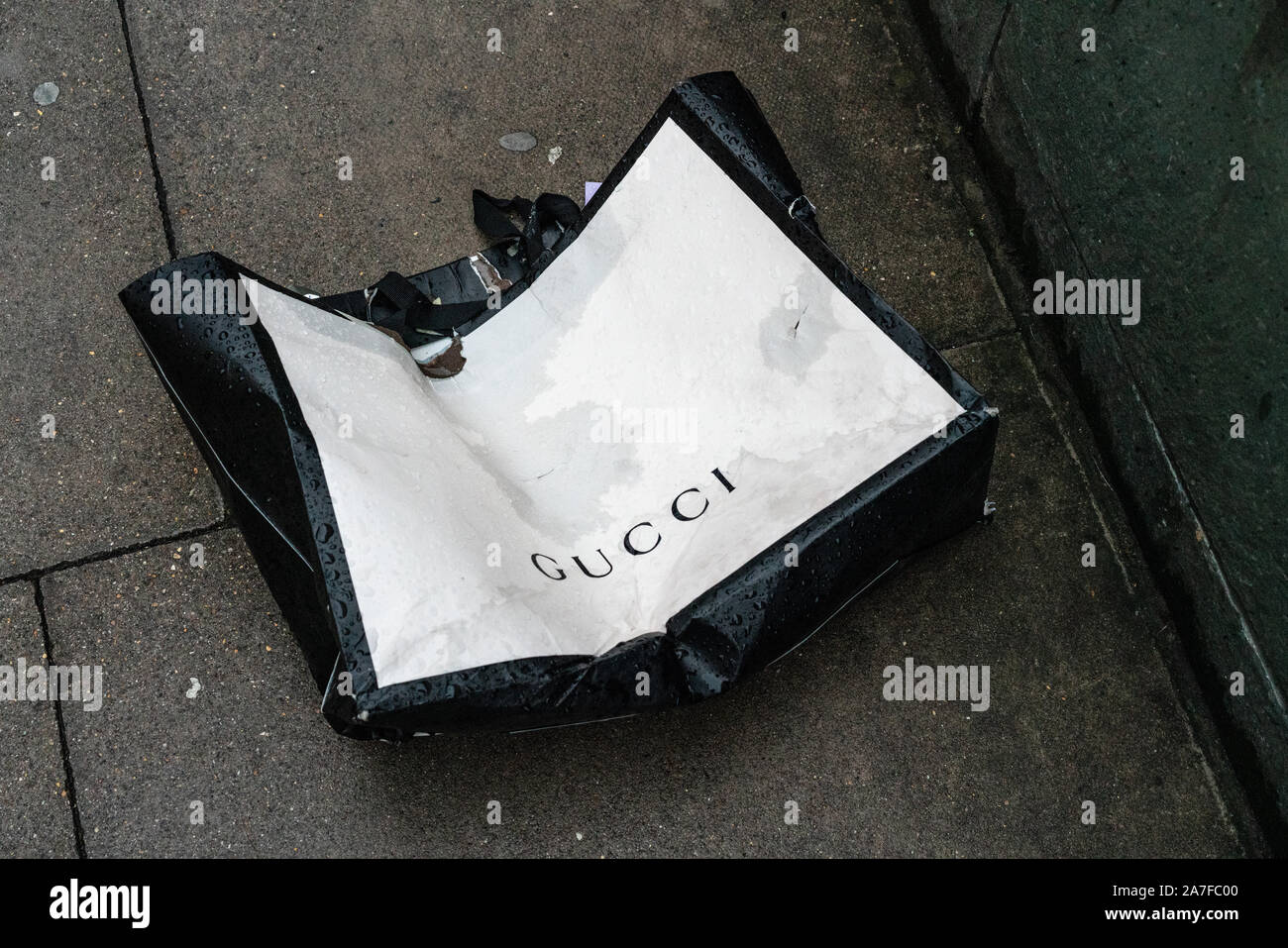 Scartato Gucci sacchetto su una strada posteriore di Londra su un giorno bagnato Foto Stock
