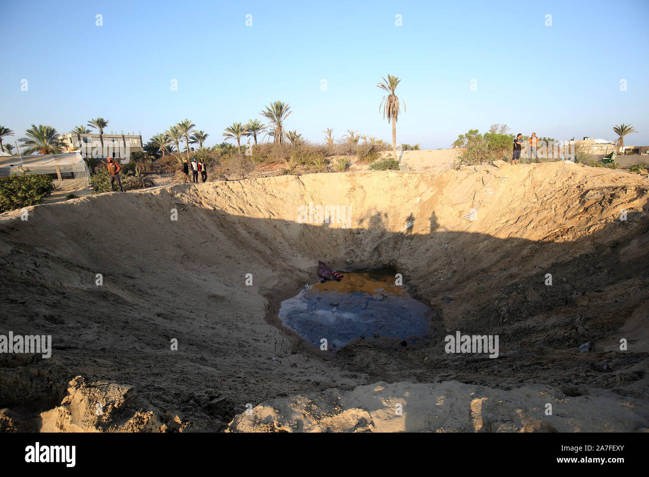 Khan Younis, Gaza. 02Nov, 2019. Gli uomini palestinesi a piedi attorno a un cratere causato da un Israeliano airstrike lanciato in Khan Yunis nel sud della striscia di Gaza il 2 novembre 2019. Decine di scioperi colpire l enclave palestinese nelle prime ore di oggi. una fonte di sicurezza a Gaza ha detto. Foto di Ismael Mohamad/UPI. Credito: UPI/Alamy Live News Foto Stock