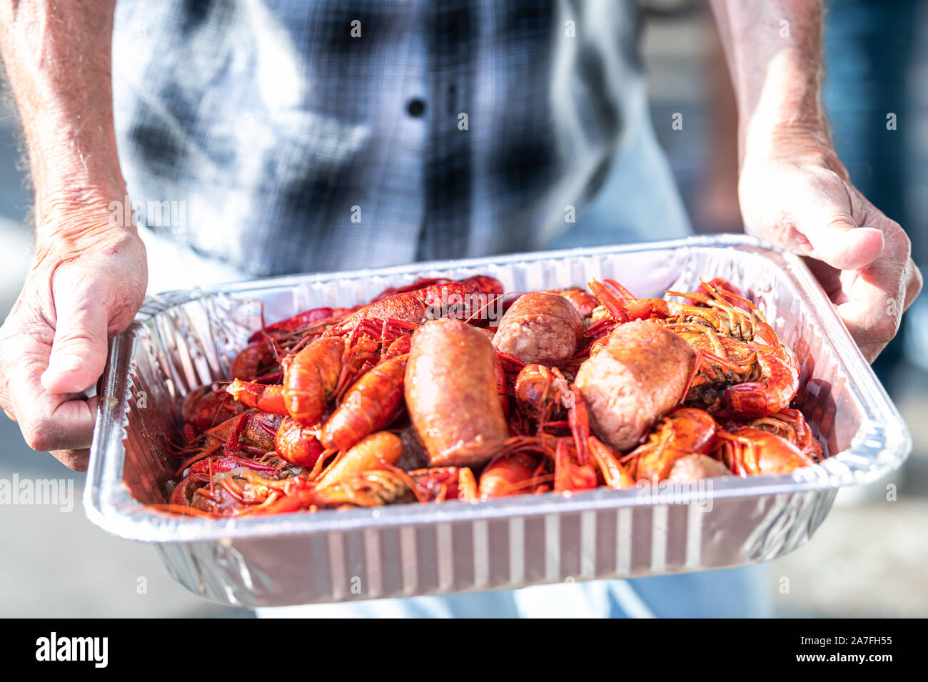 Primo piano della red aragoste e frutti di mare di aragosta con mani tenendo il vassoio di crostacei rosso in New Orleans street food Foto Stock