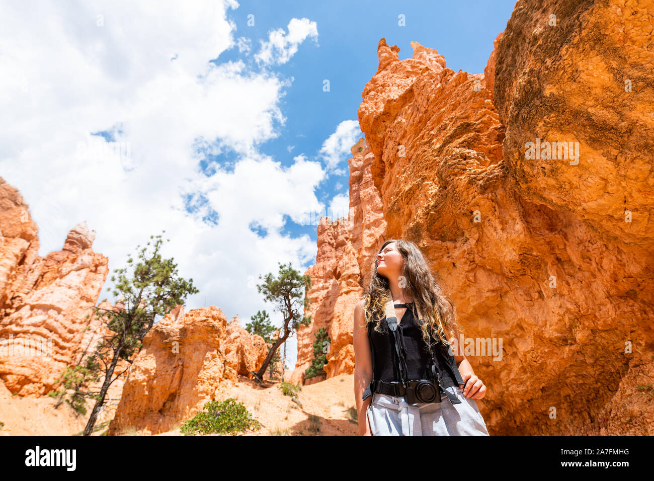 Giovane donna in piedi guardando il paesaggio del deserto vista estiva nel Parco Nazionale di Bryce Canyon su loop Navajo ampio angolo con la fotocamera e il cielo Foto Stock