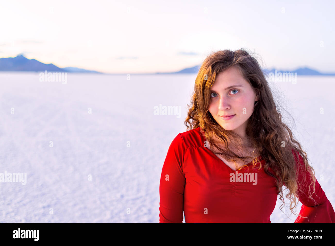 Bonneville Saline vicino a Salt Lake City, Utah al crepuscolo tramonto con viola sale rosa e il ritratto di felice giovane donna ragazza in maglietta rossa con hori Foto Stock