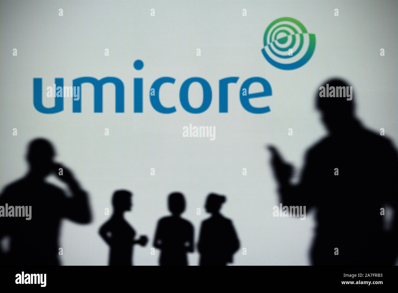 La Umicore logo è visibile su uno schermo a LED in background mentre si profila una persona utilizza uno smartphone (solo uso editoriale) Foto Stock