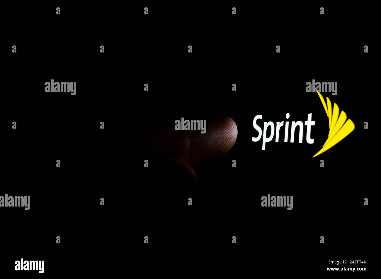 Il logo Sprint su una schermata dello smartphone in una stanza buia e un dito di toccarlo. Foto Stock