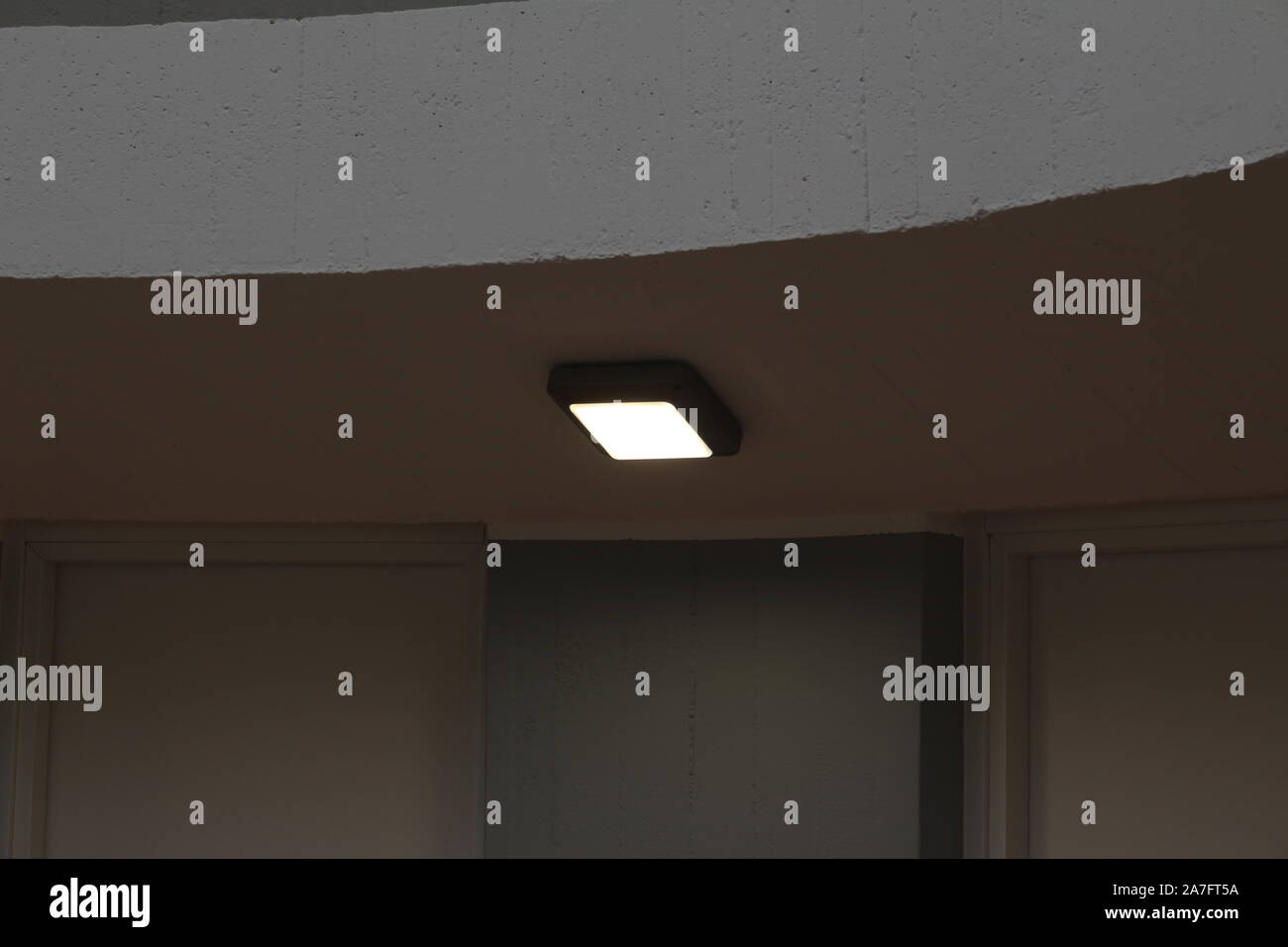 Singola bianco lampada da soffitto con luce a led, sul soffitto all'interno di un corridoio di un appartamento. Foto Stock