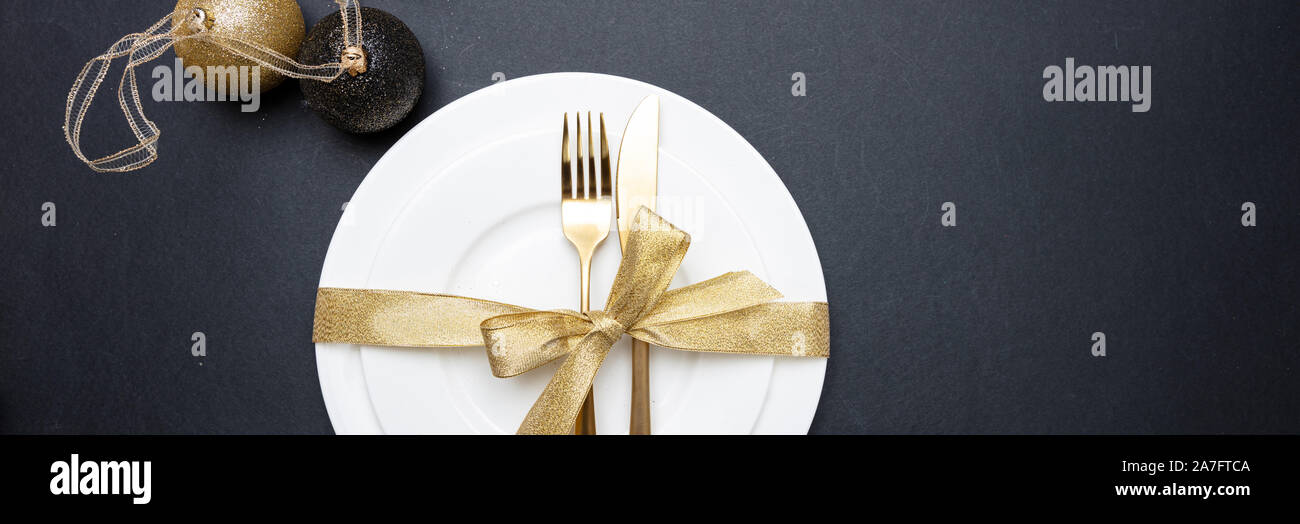 Tavola di natale l'impostazione. Posate in oro bianco e set di stoviglie su sfondo nero, banner, vista dall'alto Foto Stock