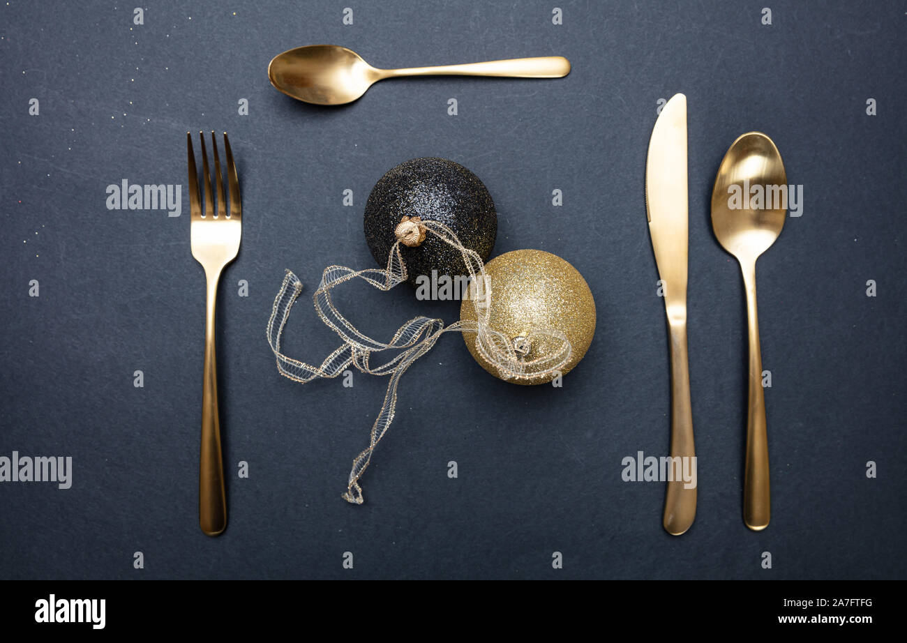 Tavola di natale l'impostazione. Oro posate e palle di Natale su sfondo nero, vista dall'alto Foto Stock