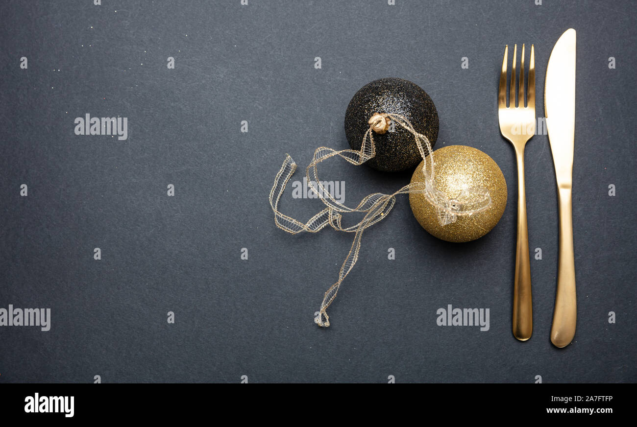 Tavola di natale l'impostazione. Oro posate e palle di Natale su sfondo nero, vista dall'alto Foto Stock