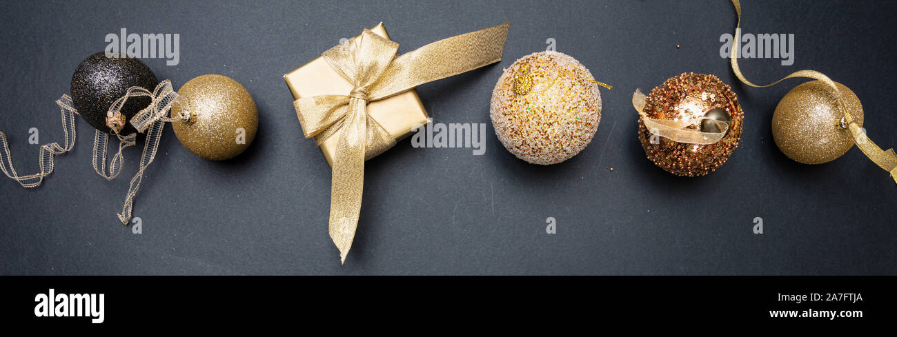 Banner di natale. Le palle di Natale e confezione regalo oro lucido contro il colore di sfondo grigio scuro, vista dall'alto Foto Stock
