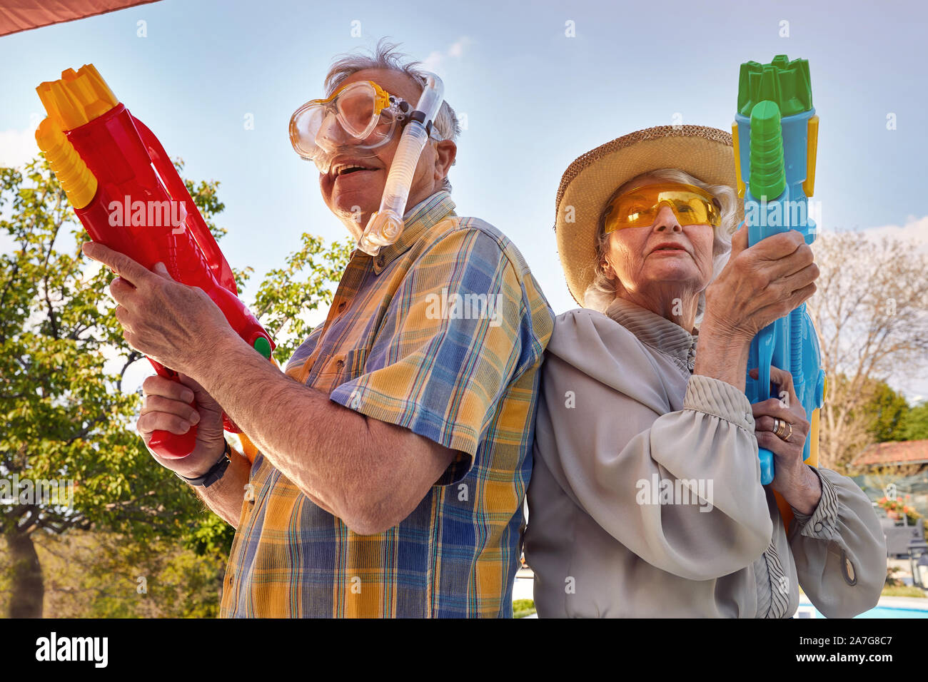 Senior moderna coppia felice divertirsi giocando con la pistola ad acqua. Foto Stock