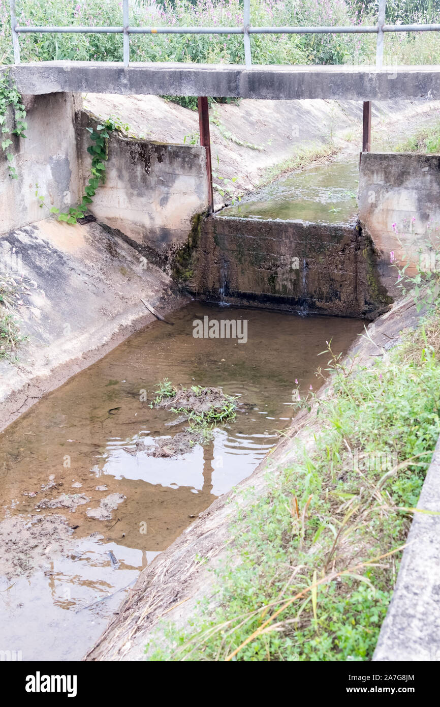 Calcestruzzo stramazzo del piccolo canale nel sistema di irrigazione per la distribuzione di acqua per la piantagione zona nella campagna della Thailandia. Foto Stock