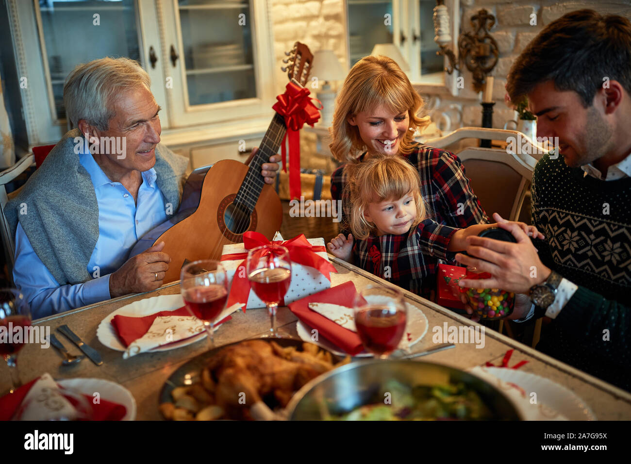 La famiglia felice con la canzone celebrare il Natale a cena Foto Stock