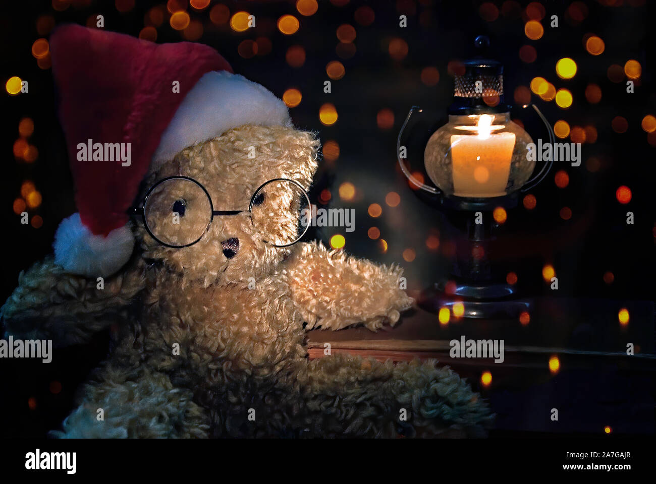 Brown pelliccia orsacchiotto con Santa cap e soffiando candela lanterna sul Natale bokeh sfondo luminoso Foto Stock