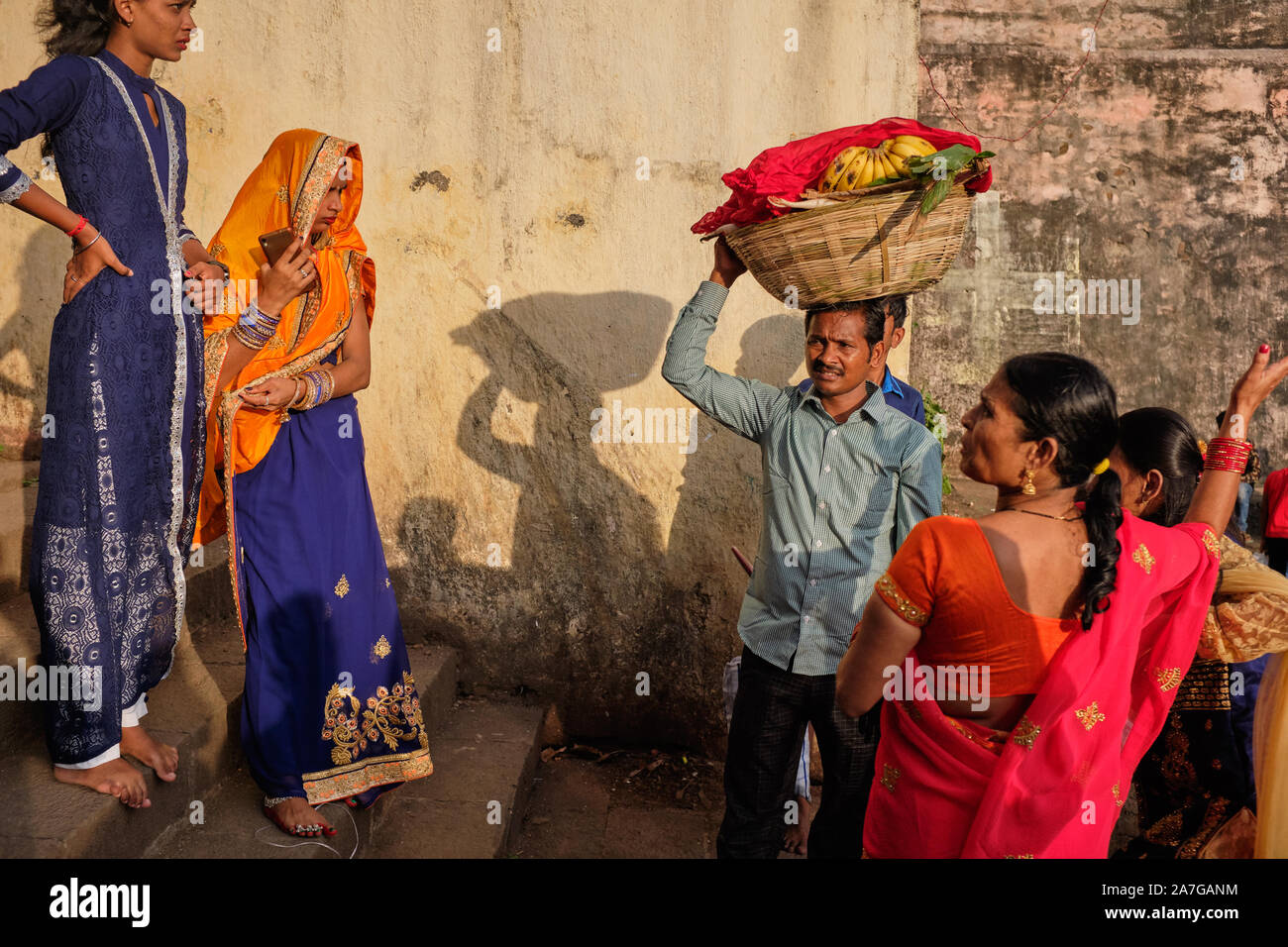 Una famiglia indù al serbatoio Banganga, Walkeshwar, Mumbai, India, durante la celebrazione della festa Chhath Puja, il padre che trasportano le offerte sacrificali Foto Stock