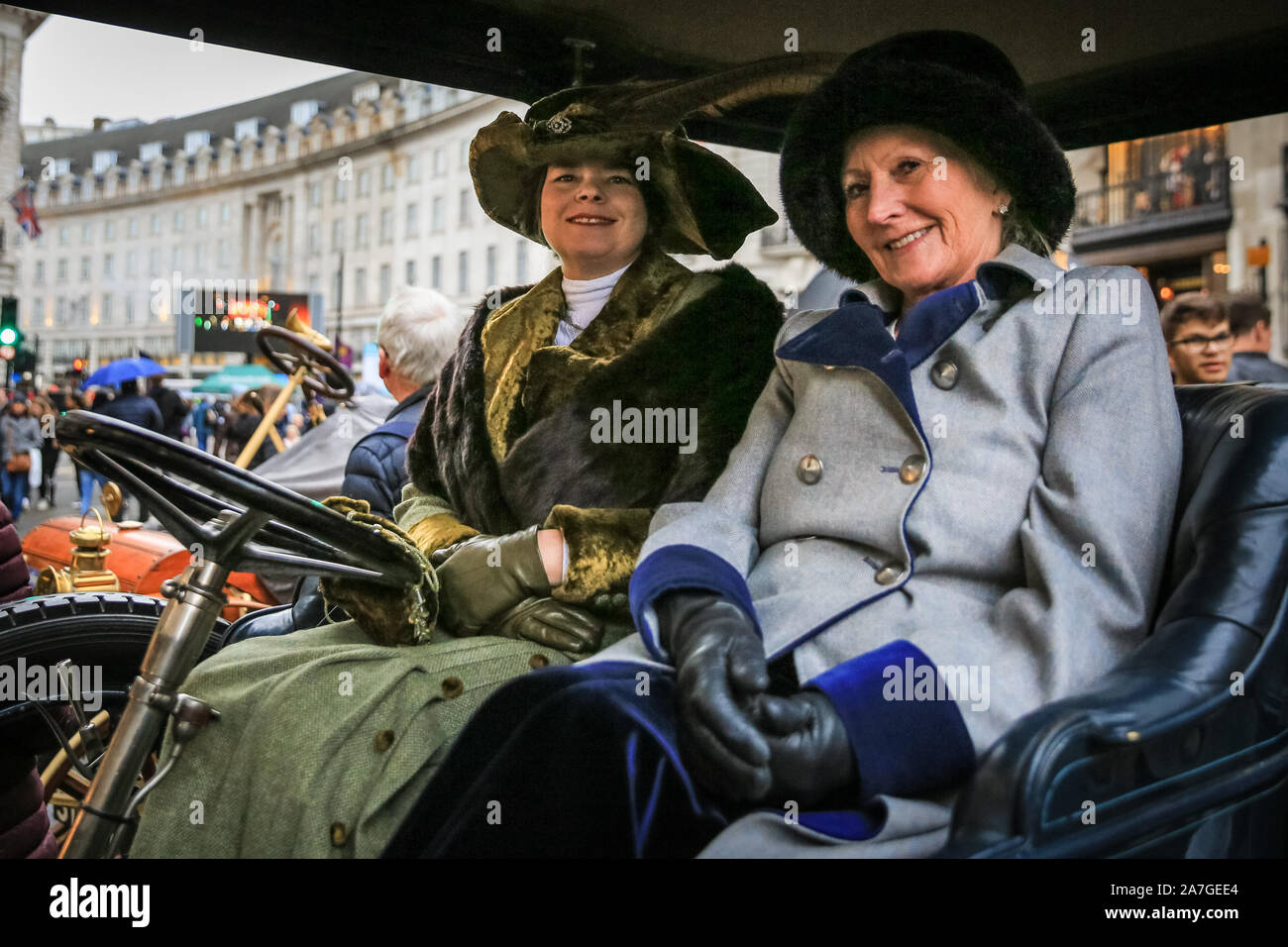 Regent Street, Londra, Regno Unito, 02 Nov 2019. Due signore in abiti in stile vittoriano in un auto classica, parte del Concours d'Eleganza di auto d'epoca, con oltre 100 pre-1905 motori. London Regent Street è pedonale per il giorno per ospitare il percorso annuale 66 Regent Street Motor Show, dotata di uno spettro completo di belle auto sul display per il pubblico, dal classico motori al famoso supercars, ultra bassa dei veicoli elettrici e iconico Route 66 americana automobili. Credito: Imageplotter/Alamy Live News Foto Stock