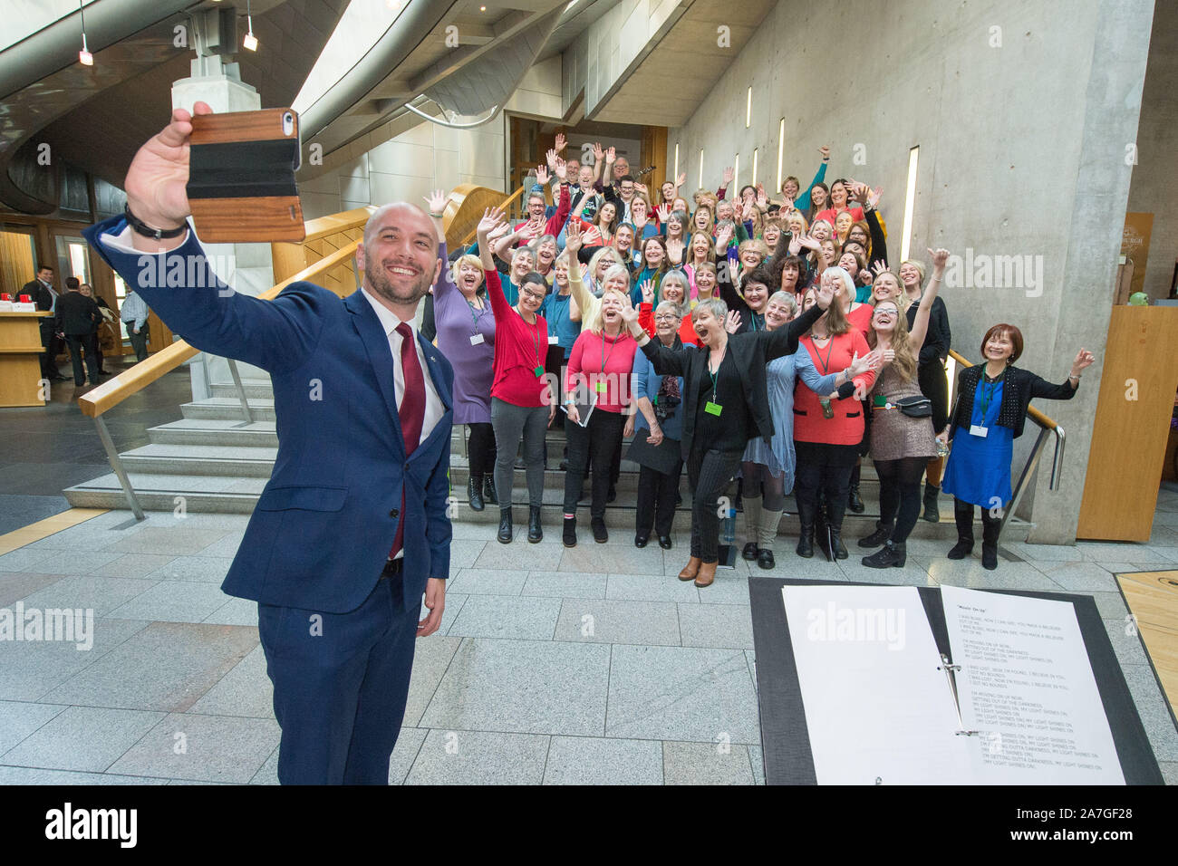 Edinburgh, Regno Unito. Il 31 ottobre 2019. Nella foto: Ben Macpherson MSP assume un selfie con il Coro Soundhouse dopo aver eseguito sui gradini del Giardino Lobby presso il Parlamento Scozzese. Soundhouse coro è un tutte le comunità di benvenuto coro, nessuna esperienza o capacità di lettura sono necessari. Formato in 2016 dal direttore musicale Heather Macleod, e ora vanta oltre 100 membri e ha eseguito in alcuni di Edimburgo più prestigiose sale tra cui Greyfriars Kirk, Usher Hall e il Queens Hall (che avallare il coro) e il parlamento scozzese! Credito: Colin Fisher/CDFIMAGES.COM Foto Stock