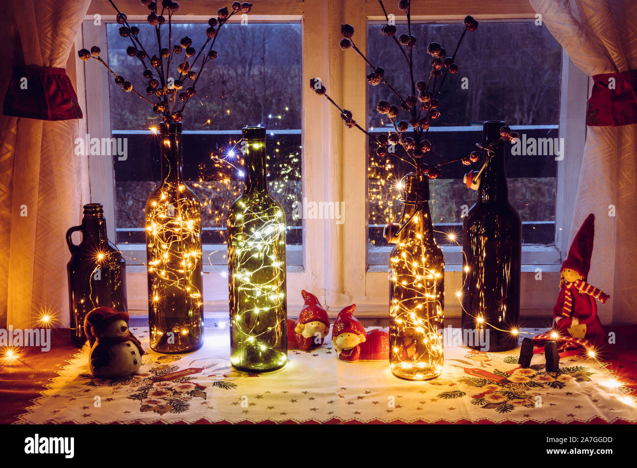 Carino e caldo natale decorazione set vintage con bottiglie di birra e di vino Bottiglie riempite con micro led luci di partito, dietro la finestra è campagna Foto Stock