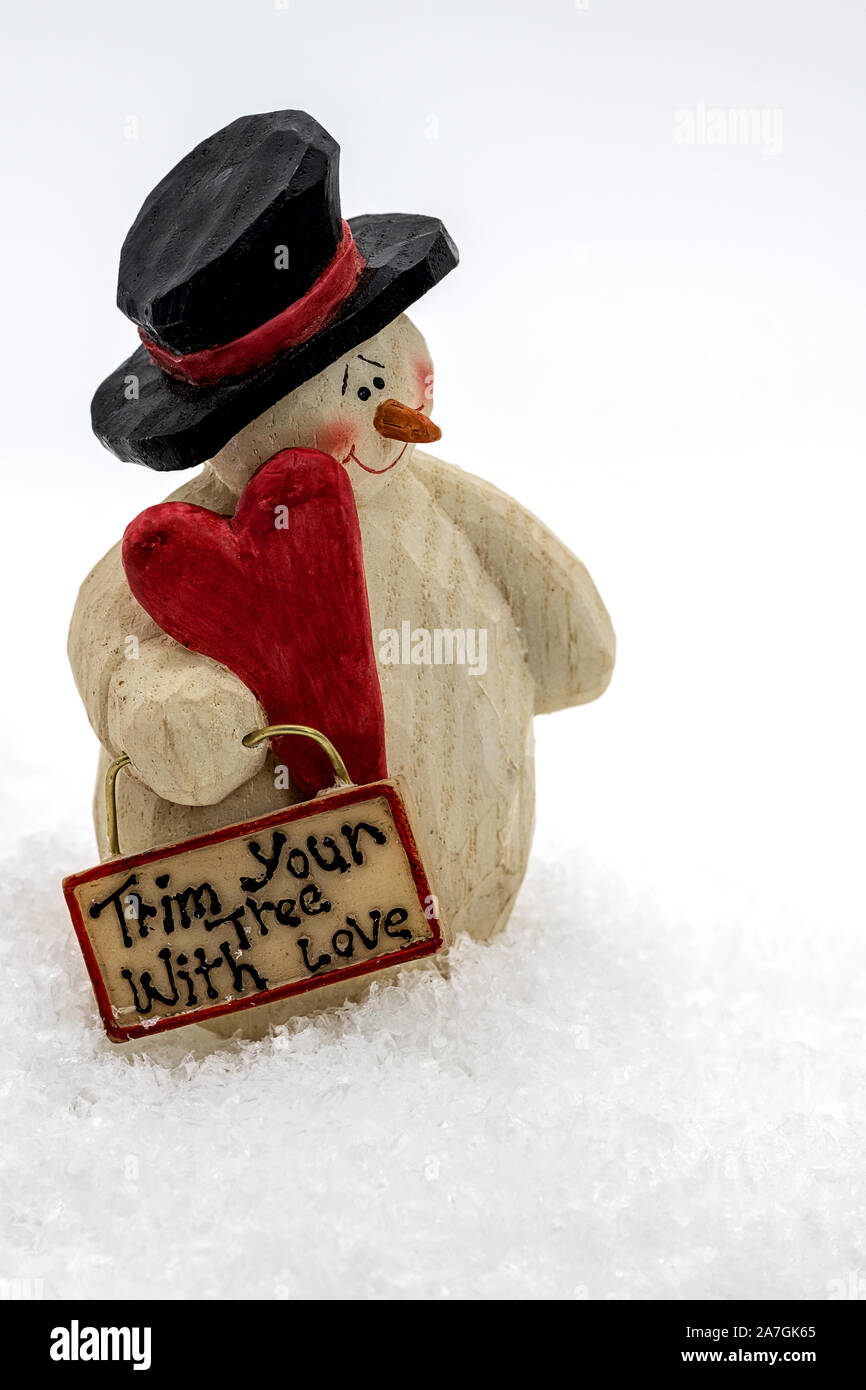 Divertente pupazzo di neve in piedi nella neve tenendo un cuore e un segno nella sua mano Foto Stock