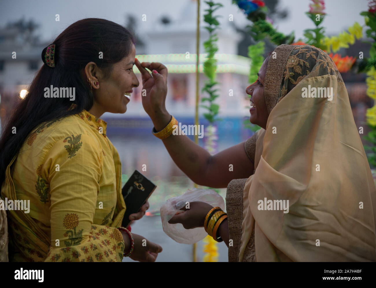 Un anziano donna offre tika ad altra donna durante il festival.Il festival Chhath, il culto del dio Sole, viene osservata in parti del Nepal e India dove i devoti rendere omaggio al sole e sua sorella 'Chhathi Maiya'. Foto Stock