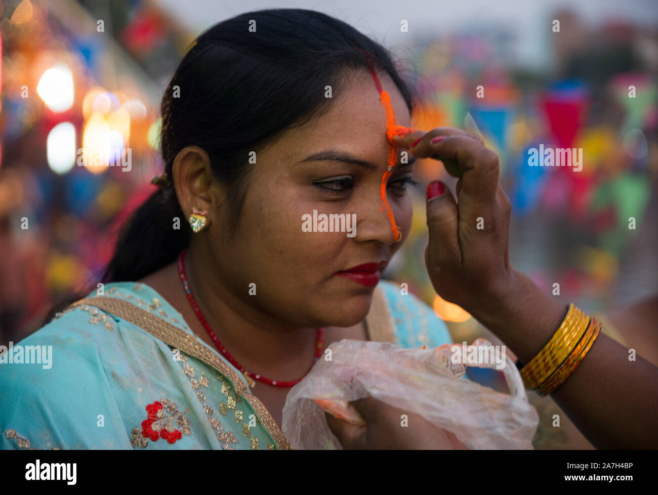Un anziano donna offre tika ad altra donna durante il festival.Il festival Chhath, il culto del dio Sole, viene osservata in parti del Nepal e India dove i devoti rendere omaggio al sole e sua sorella 'Chhathi Maiya'. Foto Stock