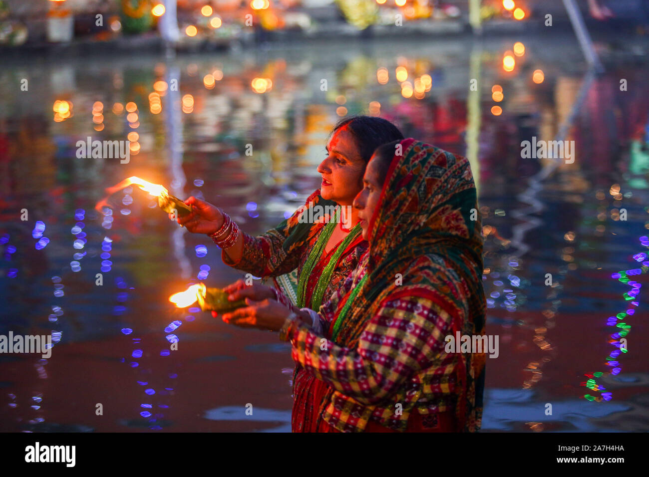 Devoti indù stand presso il fiume Bagmati a offrire preghiere al sole di setting durante il festival di Chhath.Chhath festival, noto anche come Surya Pooja (culto del sole), viene osservata nel Nepal orientale e parti dell India dove viene reso omaggio al sole e acqua gli dèi. Durante il festival di Chhath, devoti subiscono una rapida e offrono acqua e latte al dio del sole all'alba e al tramonto. La dea che è adorato durante la Puja Chhath è noto come Chhathi Maiya. Il Chhath Puja viene eseguito al fine di ringraziare Dio del sole per sostenere la vita sulla terra e di chiedere la concessione di alcuni desideri. Foto Stock