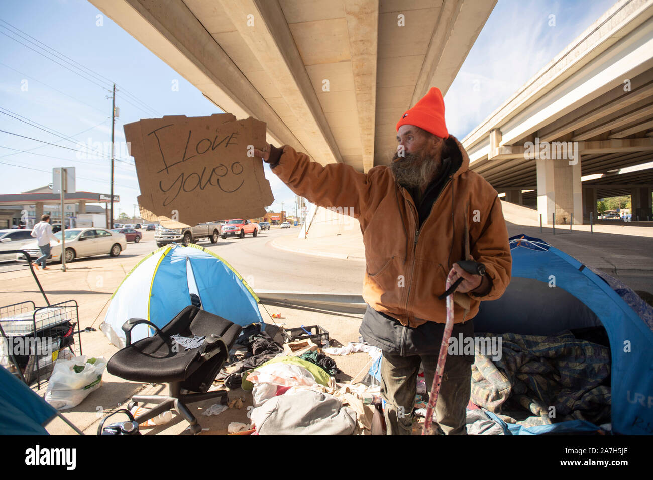 Giorni prima di una repressione minacciato dal governatore del Texas Greg Abbott sul diritto pubblico-di-modo camping, senzatetto Texans, inclusi "Corky', vi aspettano al governatore e autostrada azioni dipartimento di Austin. "Corky' contiene un segno che egli impiega per panhandling presso un vicino incrocio stradale. Foto Stock