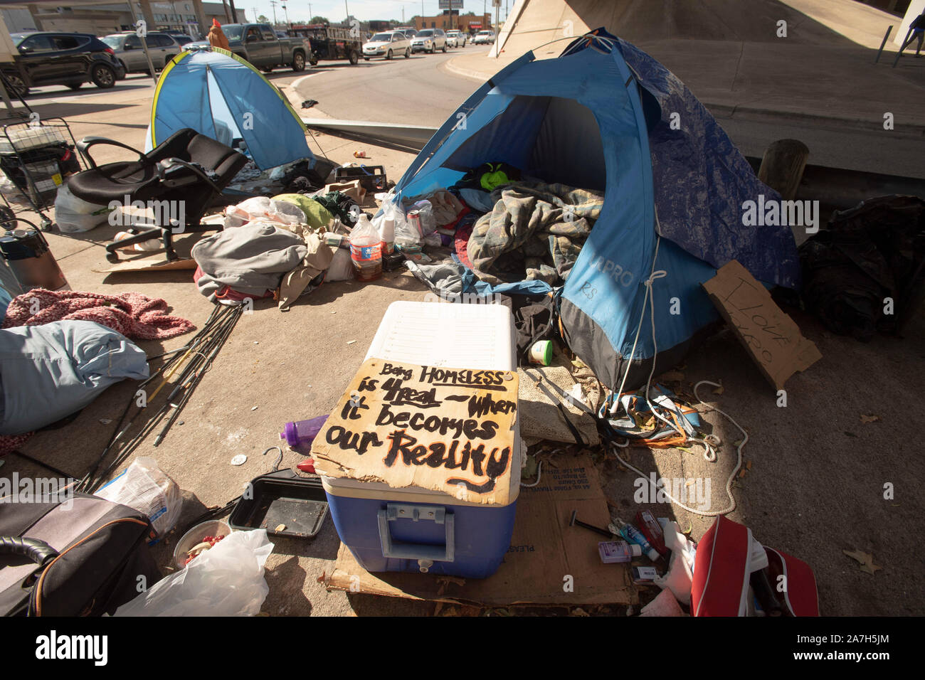 Giorni prima di una repressione minacciato dal governatore del Texas Greg Abbott sul diritto pubblico-di-modo camping, senzatetto Texans attendono l arrivo del dipartimento autostradale cleanup degli equipaggi. La maggior parte sono sicuri dove andranno come rifugi locali sono al di sopra della capacità. Il segno di fronte alla tenda recita "l'essere senzatetto è per veri--quando si tratta della nostra realtà." Foto Stock