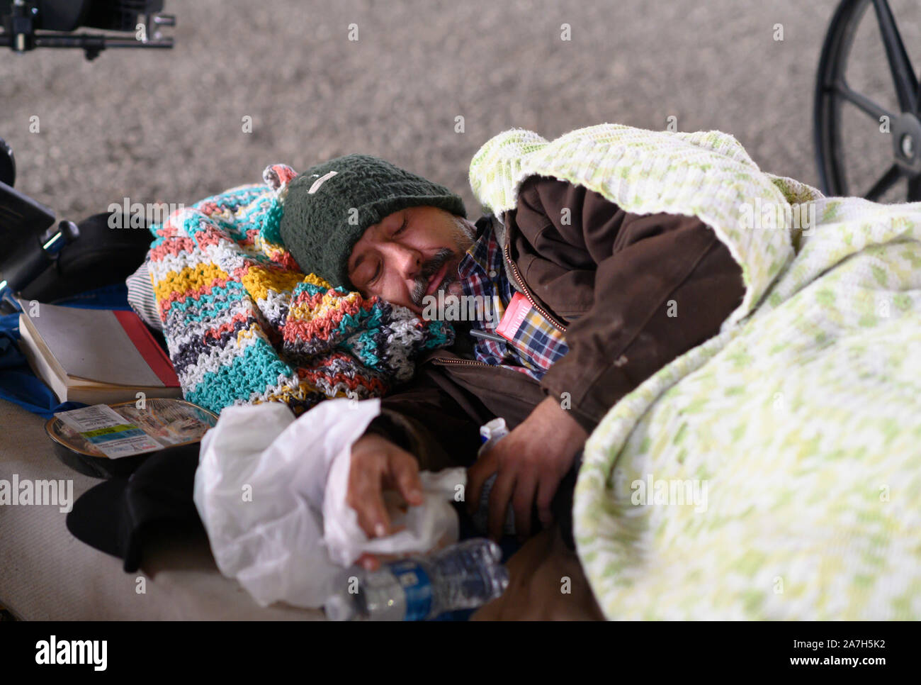 Senzatetto l'uomo cerca di stare al caldo mentre dorme in un campo di fortuna sotto un cavalcavia autostradale di Austin, Texas. Foto Stock