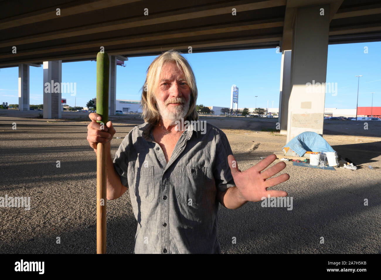 Dopo Texas Gov. Greg Abbott ha annunciato un giro di vite sulla accampamenti in spazi pubblici, un uomo pulisce l'area sotto una Austin, Texas, autostrada sopraelevata dove lui e altri hanno impostato un accampamento provvisorio per i senzatetto. Foto Stock