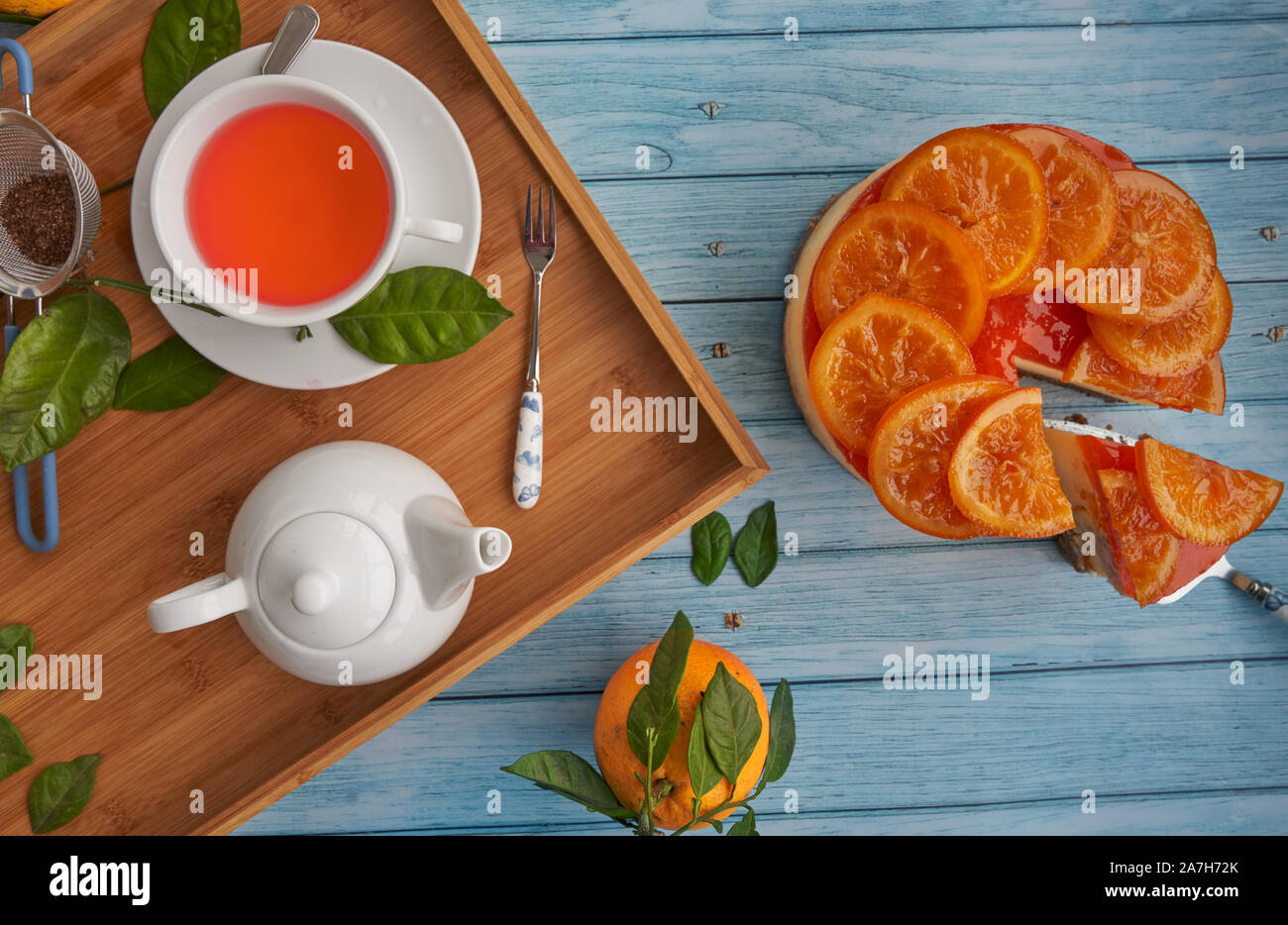 Vista dall'alto di un freddo in casa torta arancione con arancia candita sulla superficie e marmellata di colore arancione su sfondo blu. Foto Stock