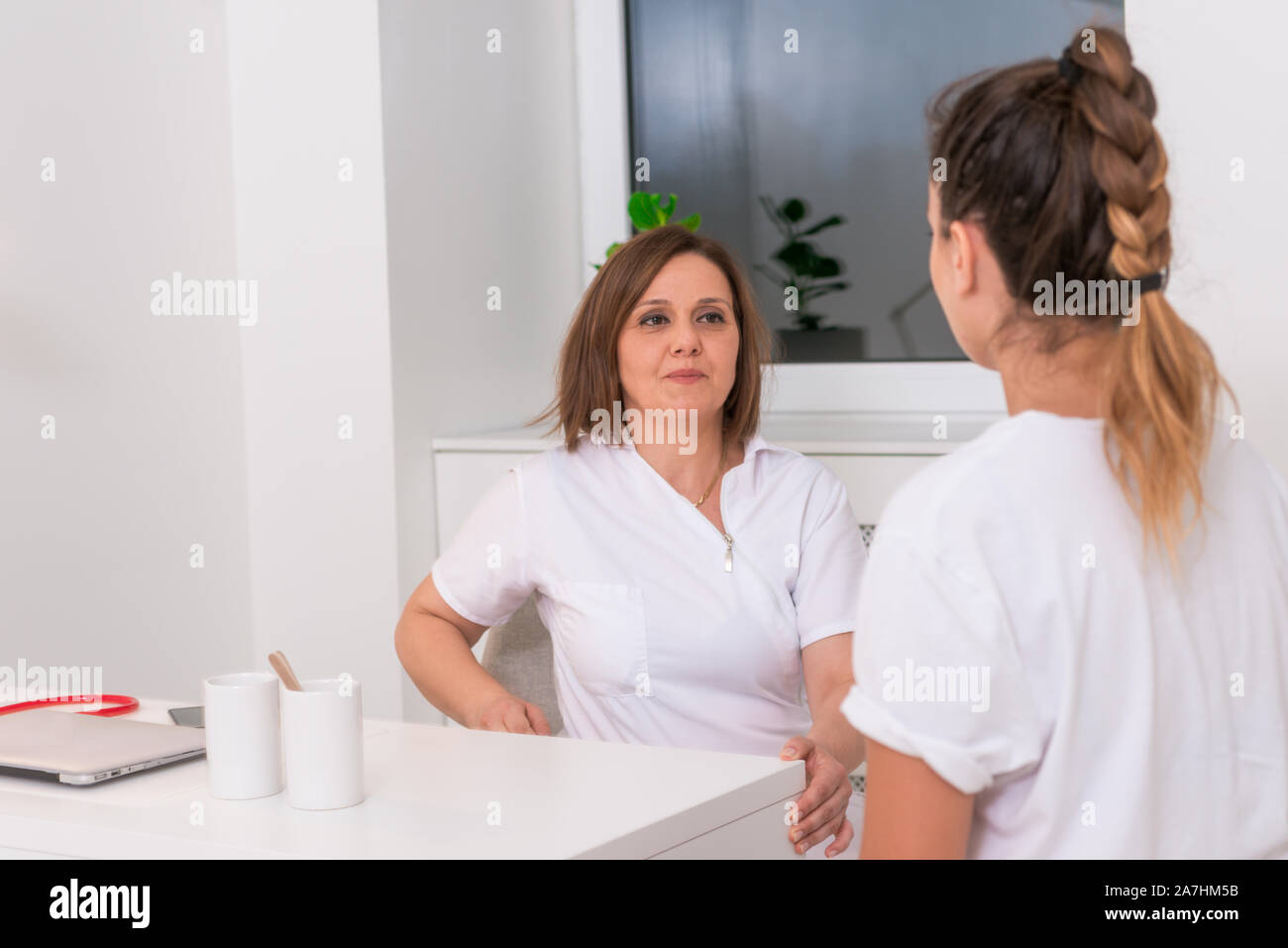 Medico donna il controllo di una ragazza adolescente la bocca con un depressore. Foto Stock