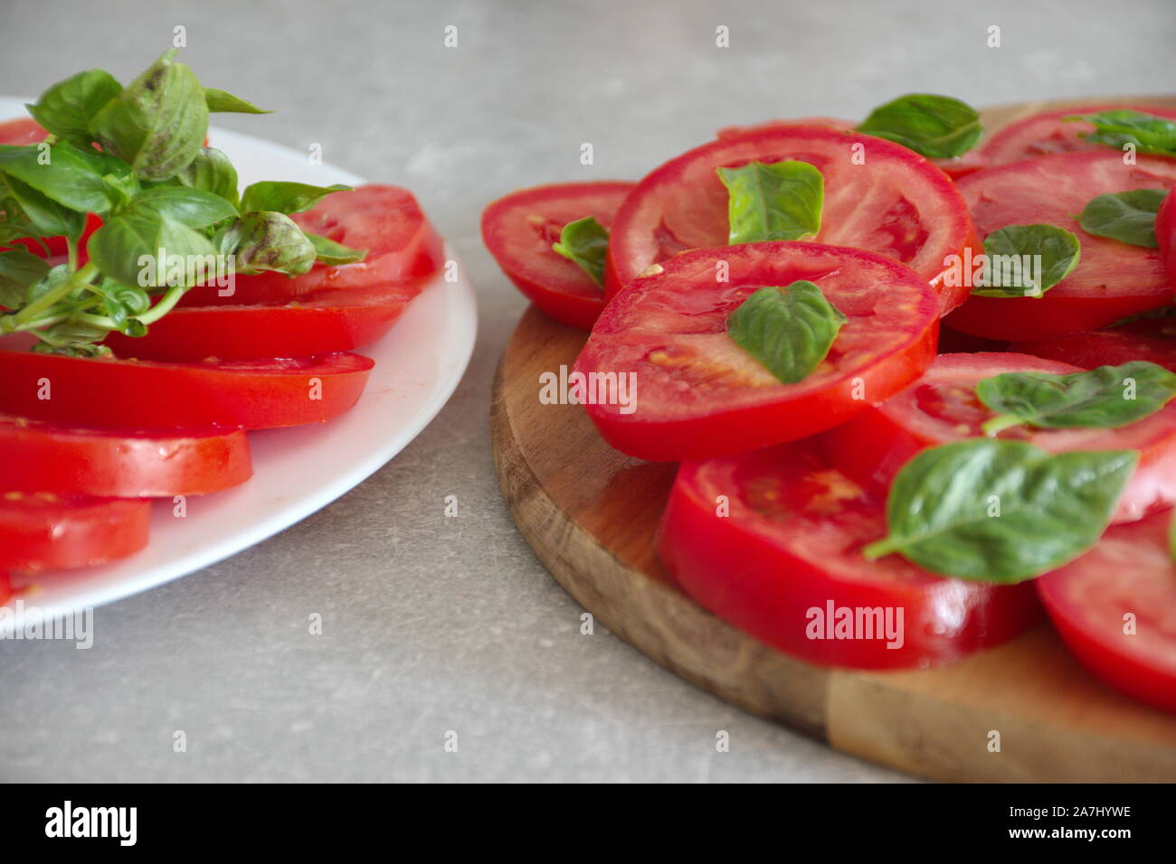 Closeup colpo di fette di pomodoro con basilico su una piastra e il bordo di taglio Foto Stock