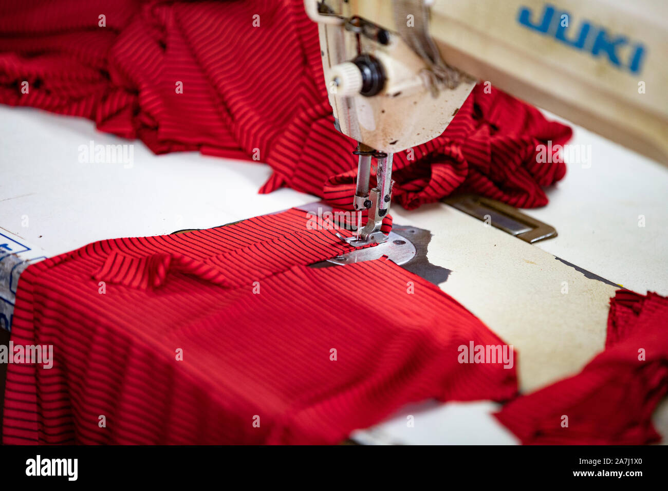 Primo piano della macchina cucitrice e il capo di abbigliamento di colore rosso Foto Stock