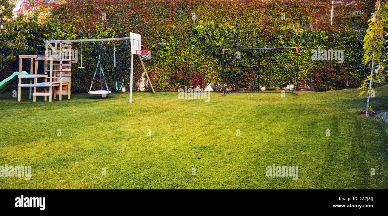 Il giardino sul retro di una casa con bambini playhouse, Basketball hoop e gol post Foto Stock