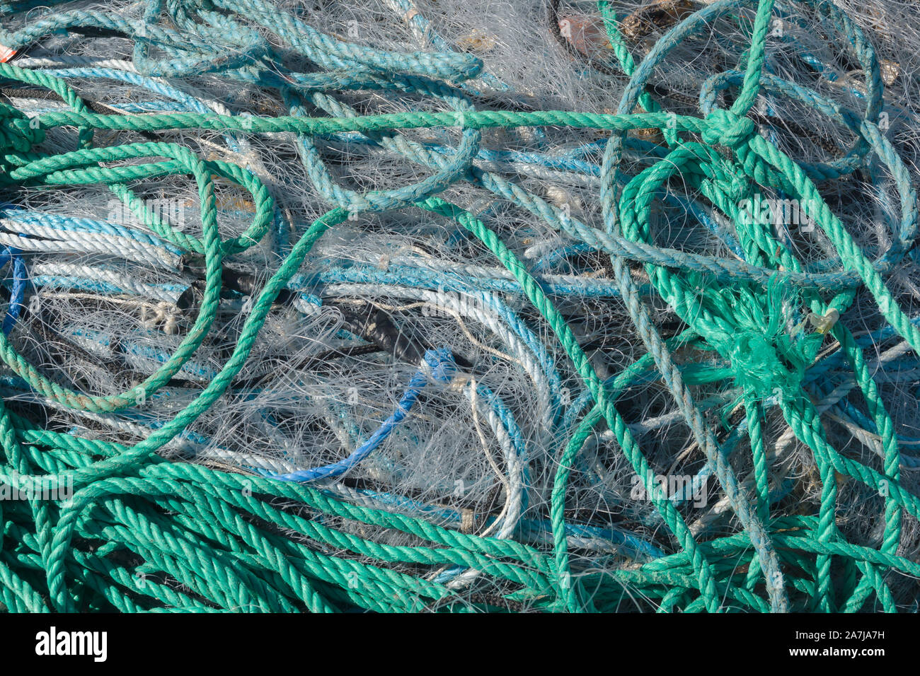 Un ingombro di reti da pesca corda di plastica e altri detriti lavato fino a una spiaggia costiera ideale per un pericolo ecologico o il concetto di inquinamento Foto Stock