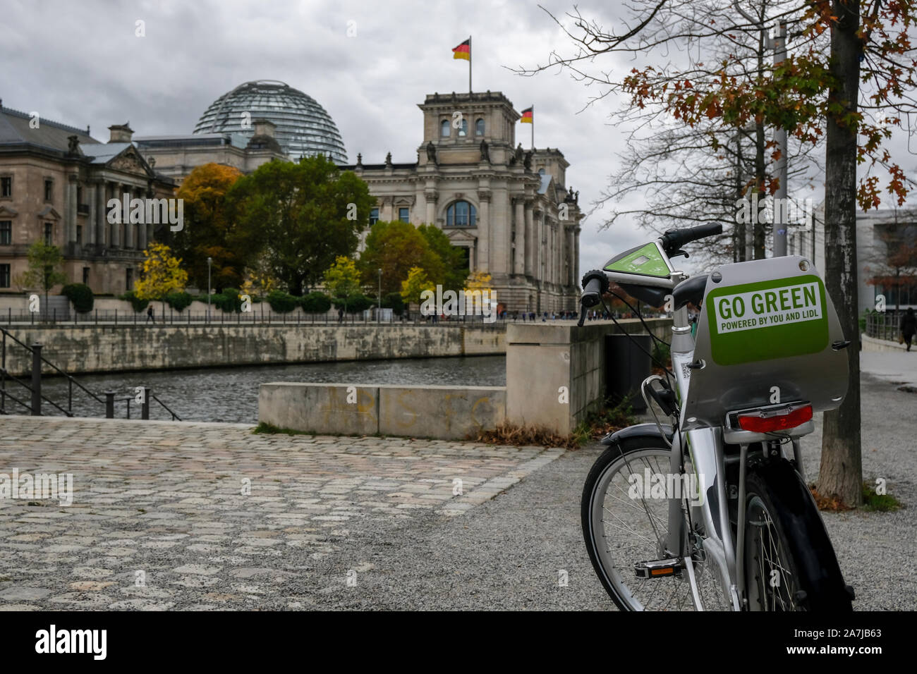 Città elettrico noleggio bici più sfocata sullo sfondo del Reichstag, cultura ecologica Foto Stock