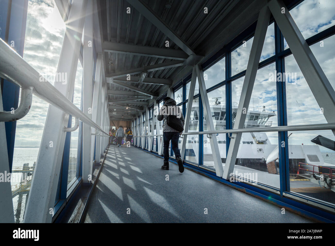 Un passeggero ferry terminal passerella con i viaggiatori a piedi con i bagagli verso un traghetto in attesa di partire. Foto Stock