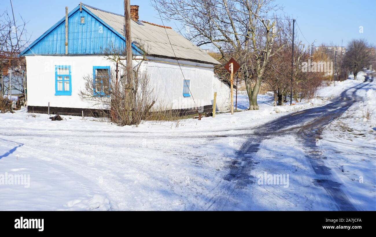In inverno il paesaggio rurale con una piccola casa e una strada di campagna. Condizioni meteo difficili con ghiaccio e grandine Foto Stock