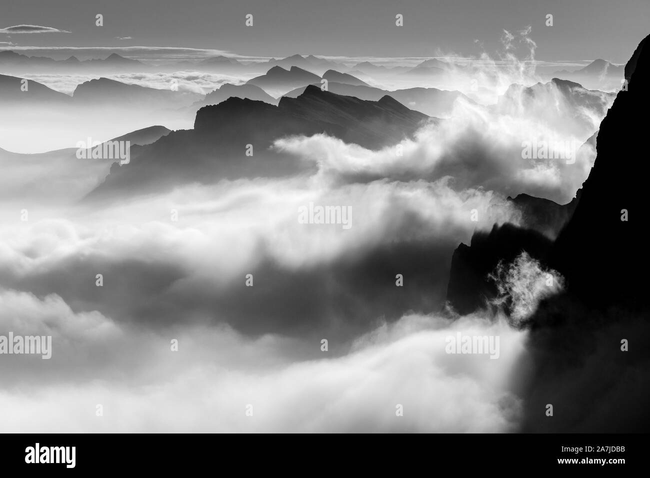 Nuvole in movimento sopra la valle all'alba. Suggestiva marea di nuvole. Paesaggio di montagna bianco e nero. Le Dolomiti. Alpi Italiane. Europa. Foto Stock