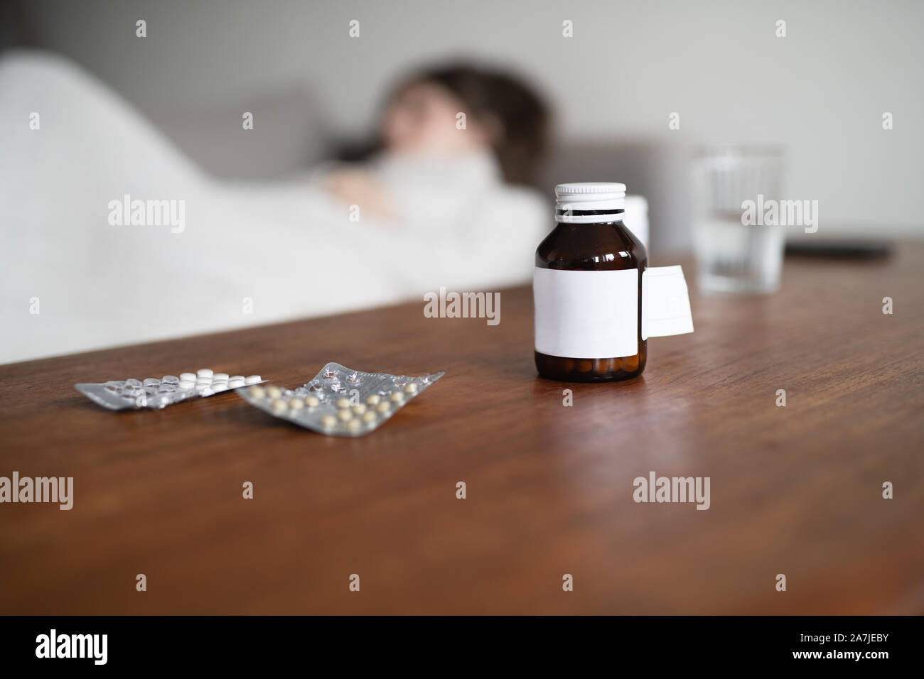 Malata in appoggio sul lettino con il flacone di farmaco in primo piano Foto Stock