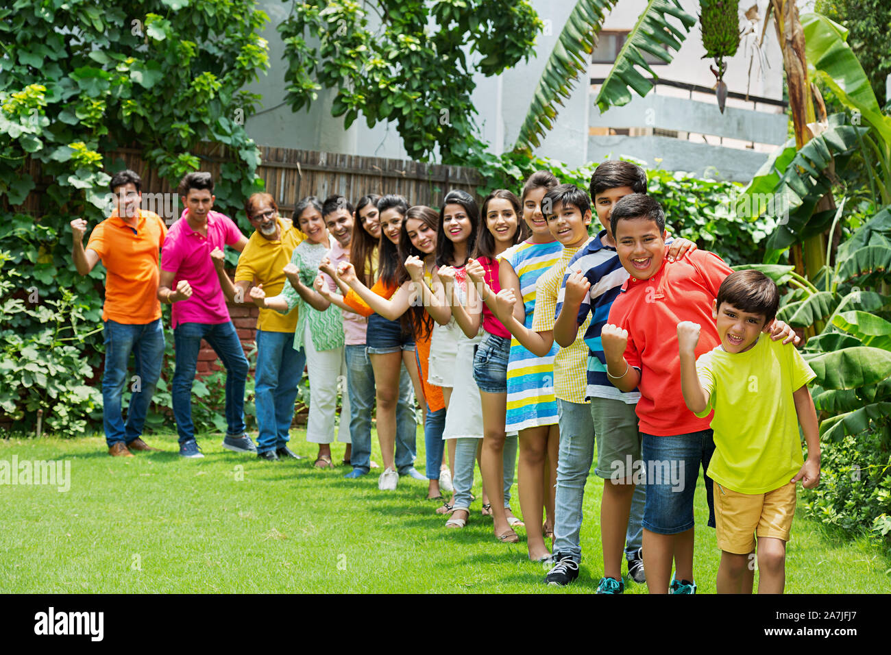 Un gruppo di grandi famiglie Stati in piedi in una linea di prodotti insieme e con le mani vincenti del pugno di celebrazione di successo nel giardino di casa Foto Stock