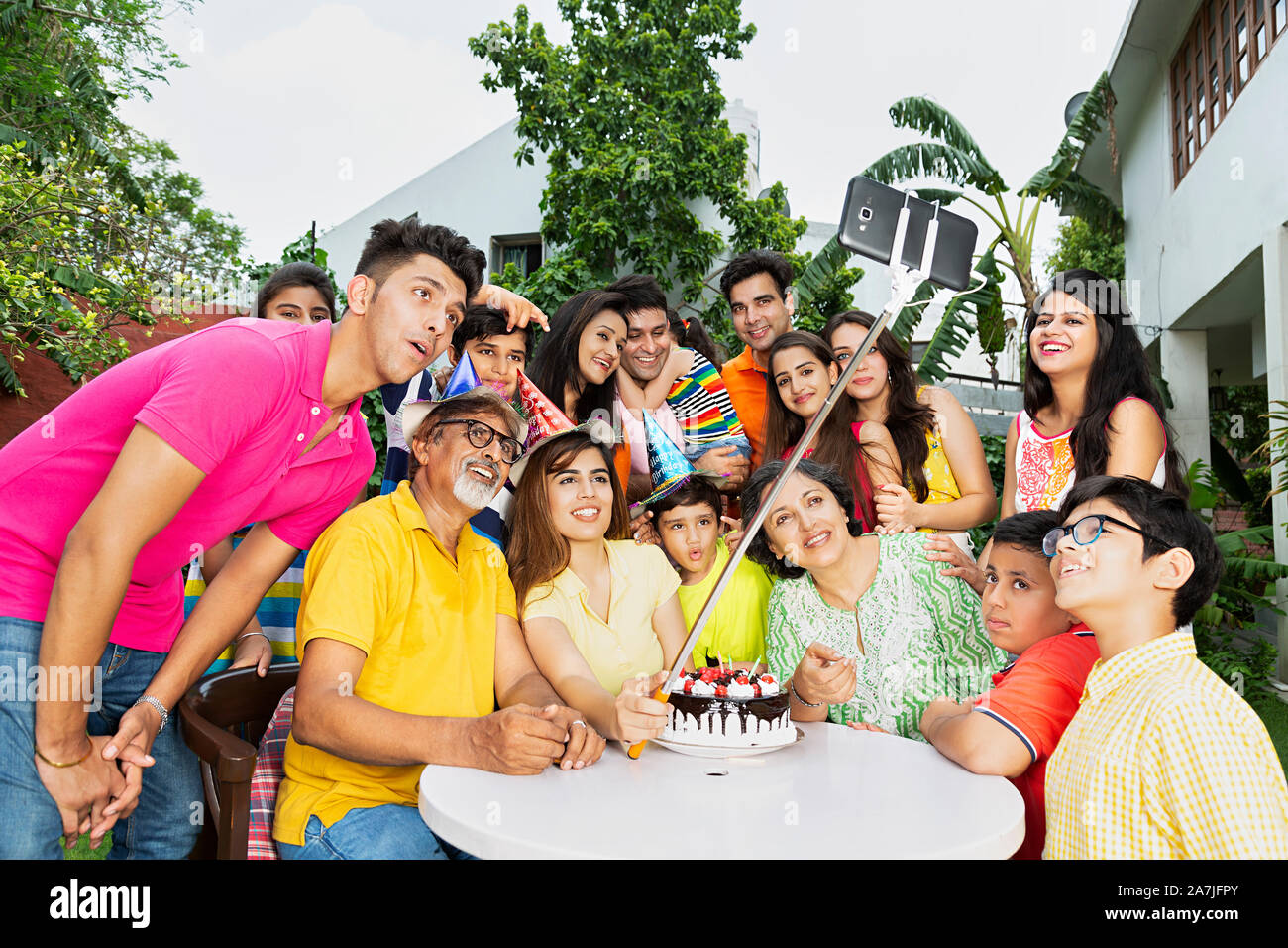 Grande gruppo di famiglia indiano membri tenendo Selfie foto con monopiede durante la festa di compleanno in cortile di casa loro Foto Stock