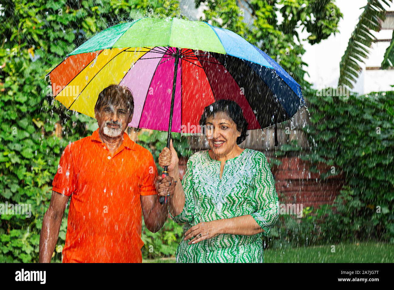 Romantica felice coppia di anziani sotto l'Ombrello in primavera nel giardino Foto Stock