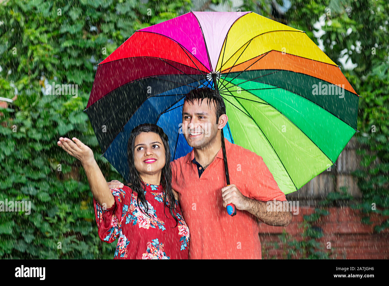 Felice di amare giovane sotto l ombrello godendo la pioggia di estate in giardino esterno Foto Stock